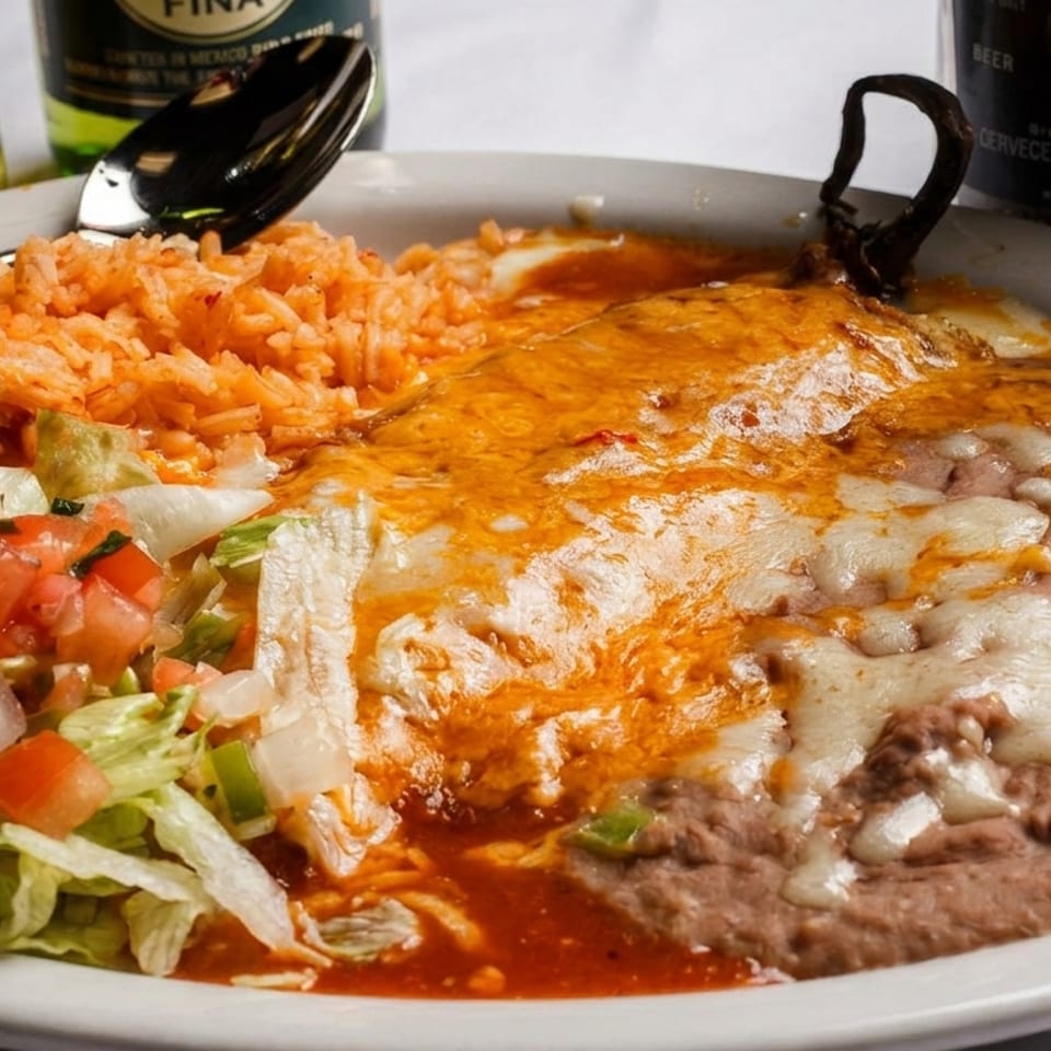 Mexican combination plate with cheese-covered enchilada, refried beans, rice, salad, and Modelo beer bottles.