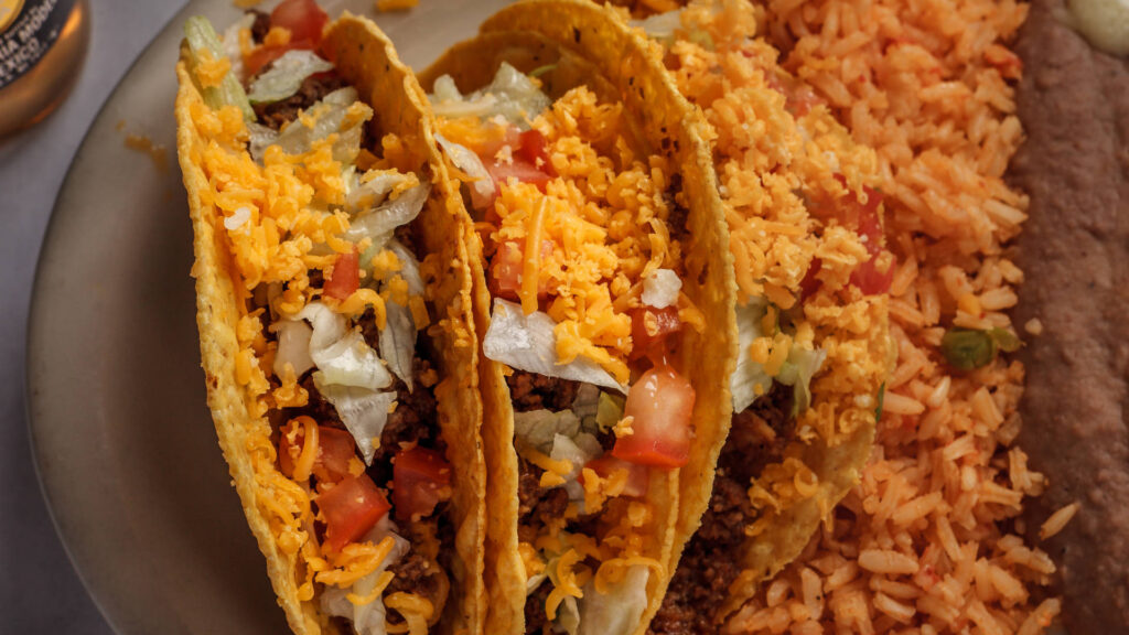 two tostada tacos with cheese and pico de gallo inside rice