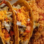 two tostada tacos with cheese and pico de gallo inside rice