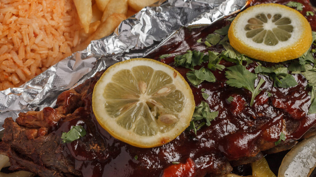grilled baby back ribs with bbq sauce lemon slices and chopped parsley rice and fries