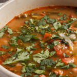 bowl of soup tomatoes beans parsley on top