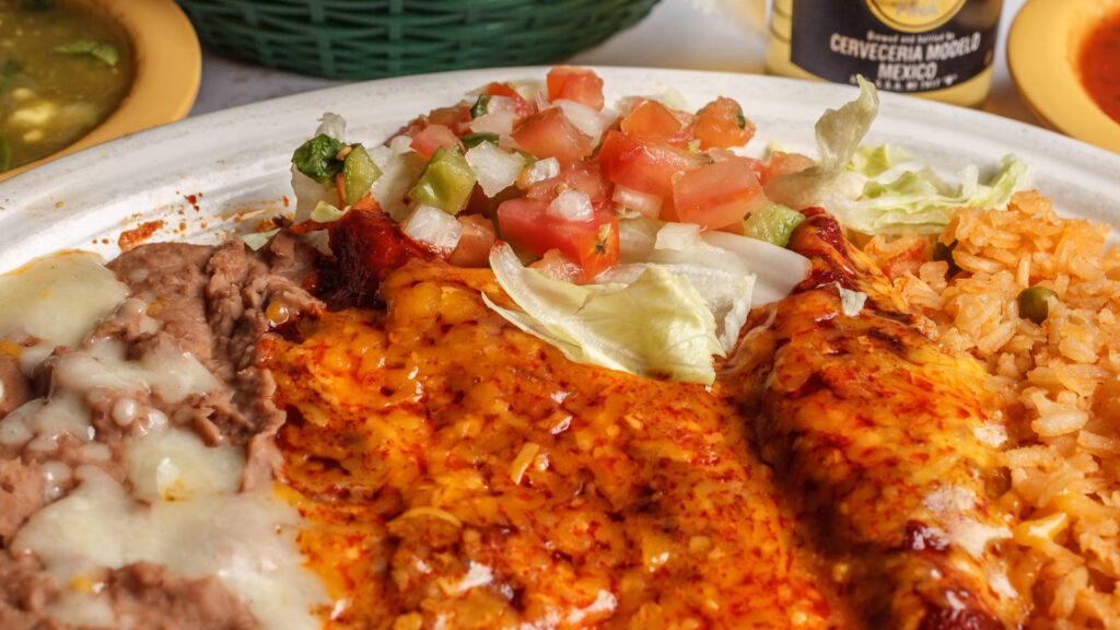 two enchiladas pico de gallo refried beens rice red sauce and cheese on top