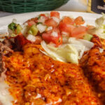 two enchiladas pico de gallo refried beens rice red sauce and cheese on top