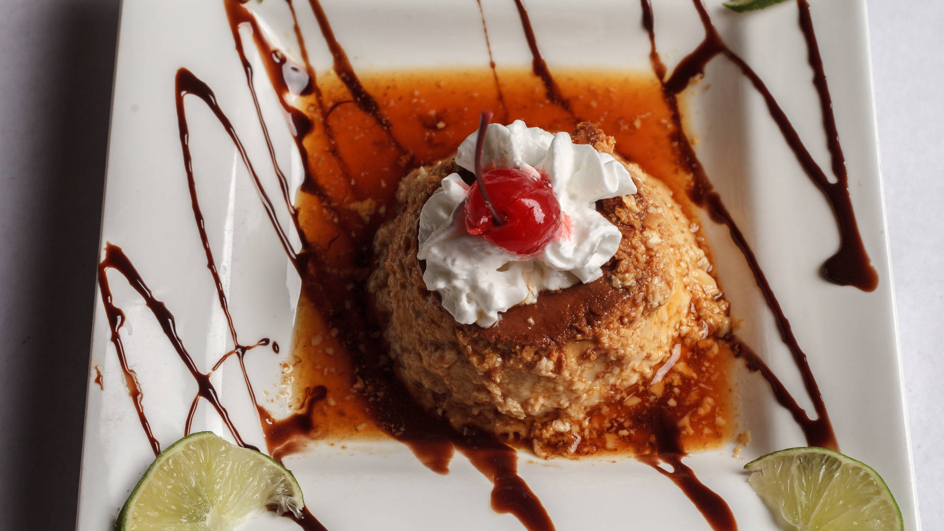 flamed flan whip cream and cherry on top plate decorated with chocolate