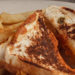 grilled sandwich cutted in half fries