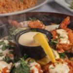 Camarones Mazatlan. grilled breaded shrimp cup with sauce a slice of lemon melted cheese on top.
