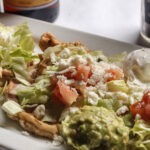 three tortillas with refried beans grilled chicken pico de gallo sour cream and guacamole