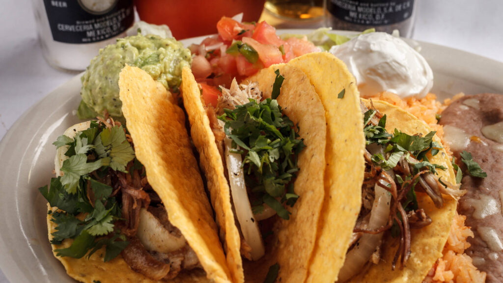 hard fried taco tortillas with meat onions cilantro pico de gallo refried beans and rice on the side
