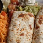 two tacos rice sauce in a cup pico de gallo sour cream